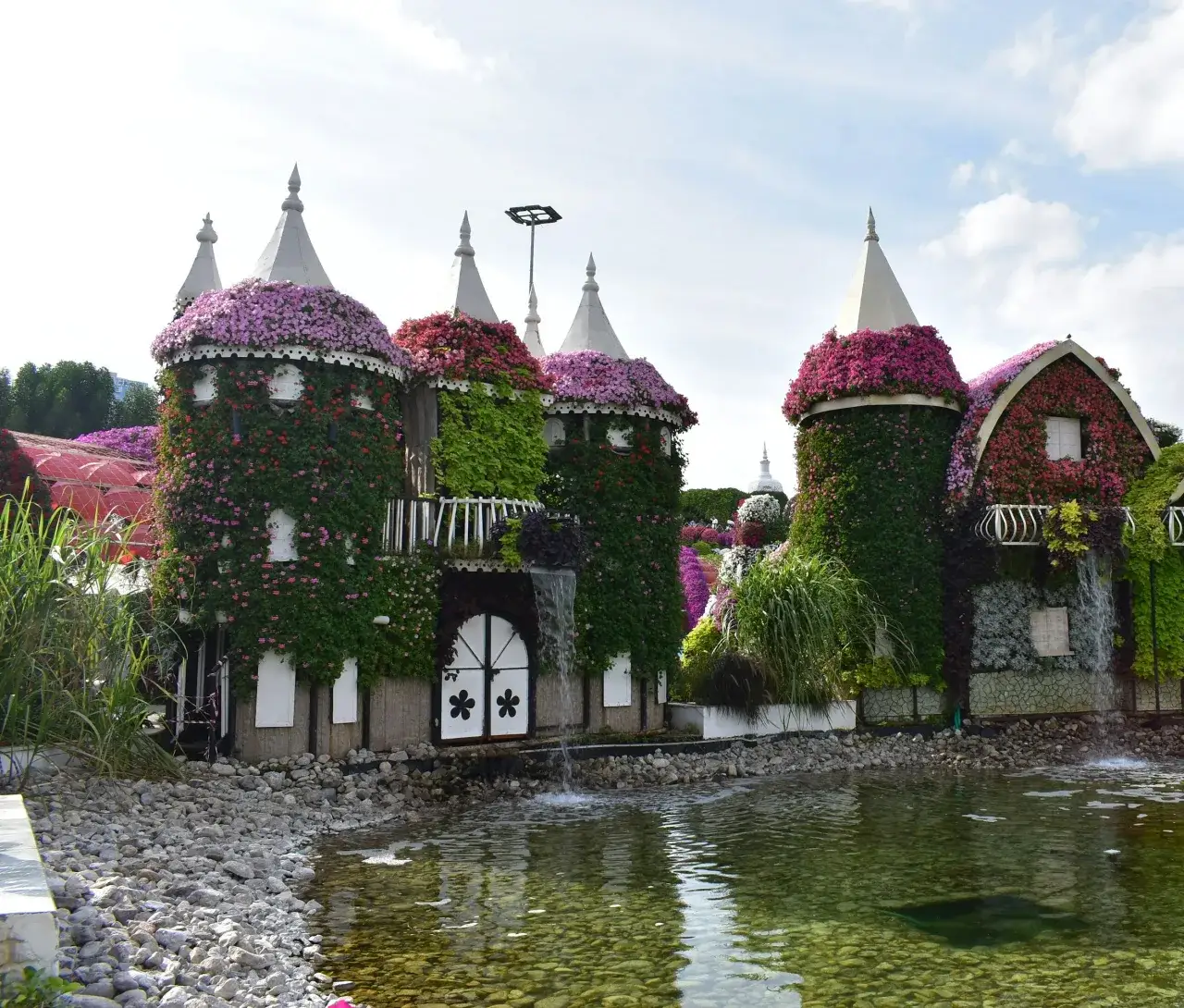Flower-covered houses and water feature at Dubai Miracle Garden in Arjan