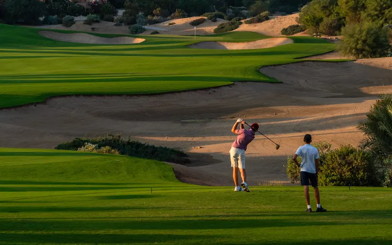 Golfers and green fairway at The Els Club, Dubai Sports City