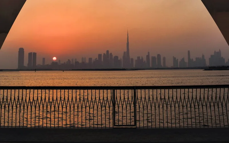 Dubai skyline at sunset seen from the sculpture-framed Creek Harbour waterfront